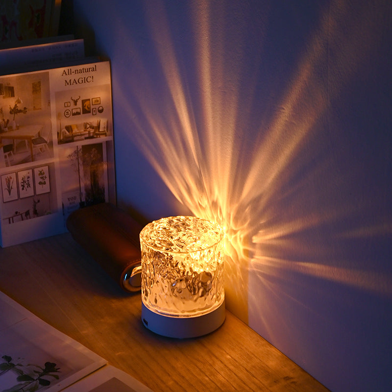 Lámpara de ondas de agua encendida con luz cálida sobre una mesa de madera